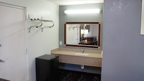 A bathroom with a sink, mirror, towel rack, and a small black cabinet.