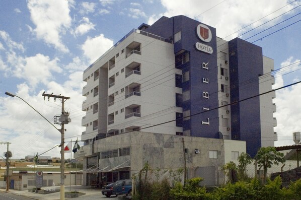 A hotel with a prominent 'LIBER' sign on the side, multiple balconies, and a parking area in front. - Liber Hotel Nova Serrana (Nova Serrana)