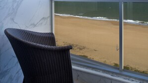 A room with a view of a beach, a wicker chair, and a marble wall. - Royal Atlântica Macaé Hotel (Macaé)