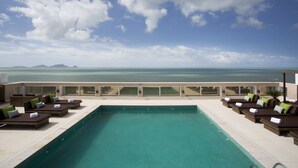 A poolside area with lounge chairs and a view of the ocean. - Royal Atlântica Macaé Hotel (Macaé)