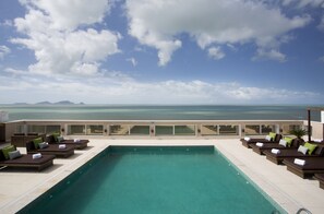 A poolside area with lounge chairs and a view of the ocean. - Royal Atlântica Macaé Hotel (Macaé)