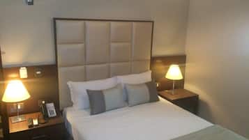 A hotel room with a large bed, two bedside tables with lamps, a phone, and a small drawer.