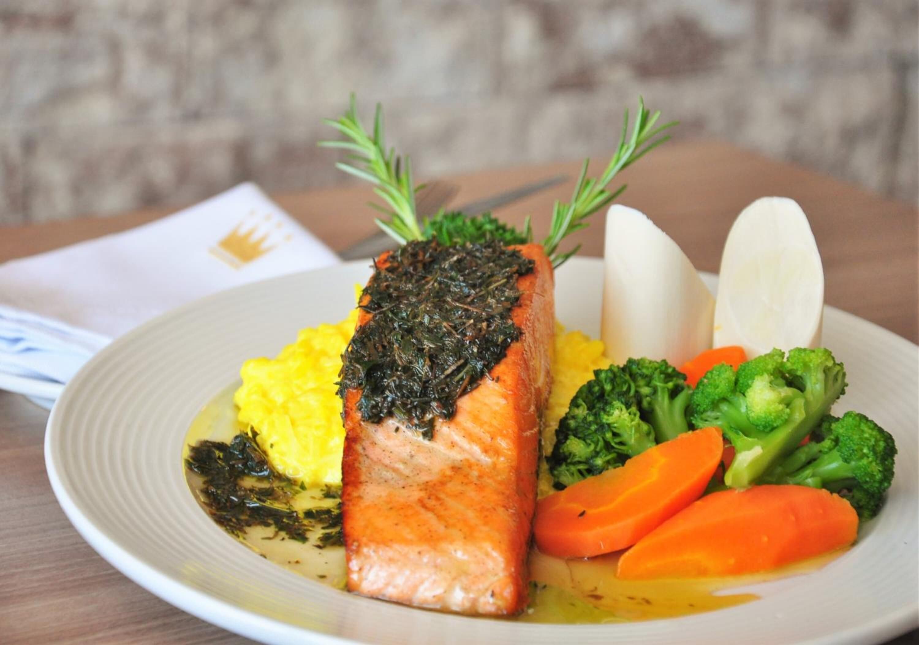 Une assiette de nourriture comprenant du saumon, des brocolis, des carottes et des pommes de terre.