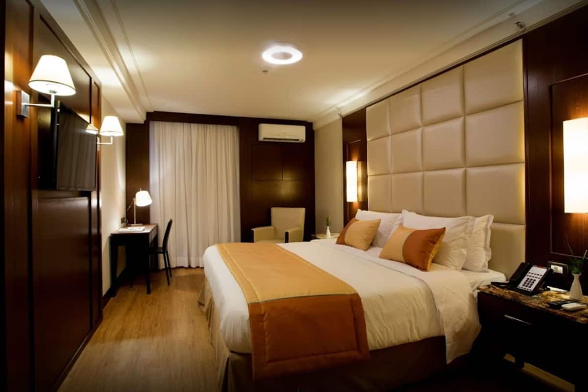 A hotel room with a large bed, bedside tables, a desk, and a chair.