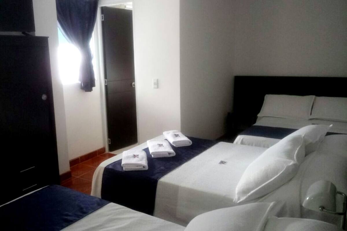 Habitación de hotel con dos camas, un armario y la puerta del baño.