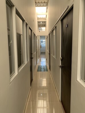 A long, narrow hallway with doors on both sides, leading to a bright room at the end. - Hotel Casa Guillermo (Bogotá)