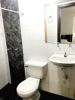 A bathroom with a toilet, sink, and mirror. - Hotel Casa Guillermo (Bogotá)