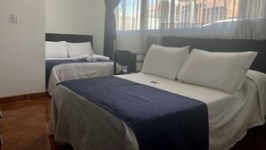 Una habitación de hotel con dos camas, una silla y una ventana con cortinas.