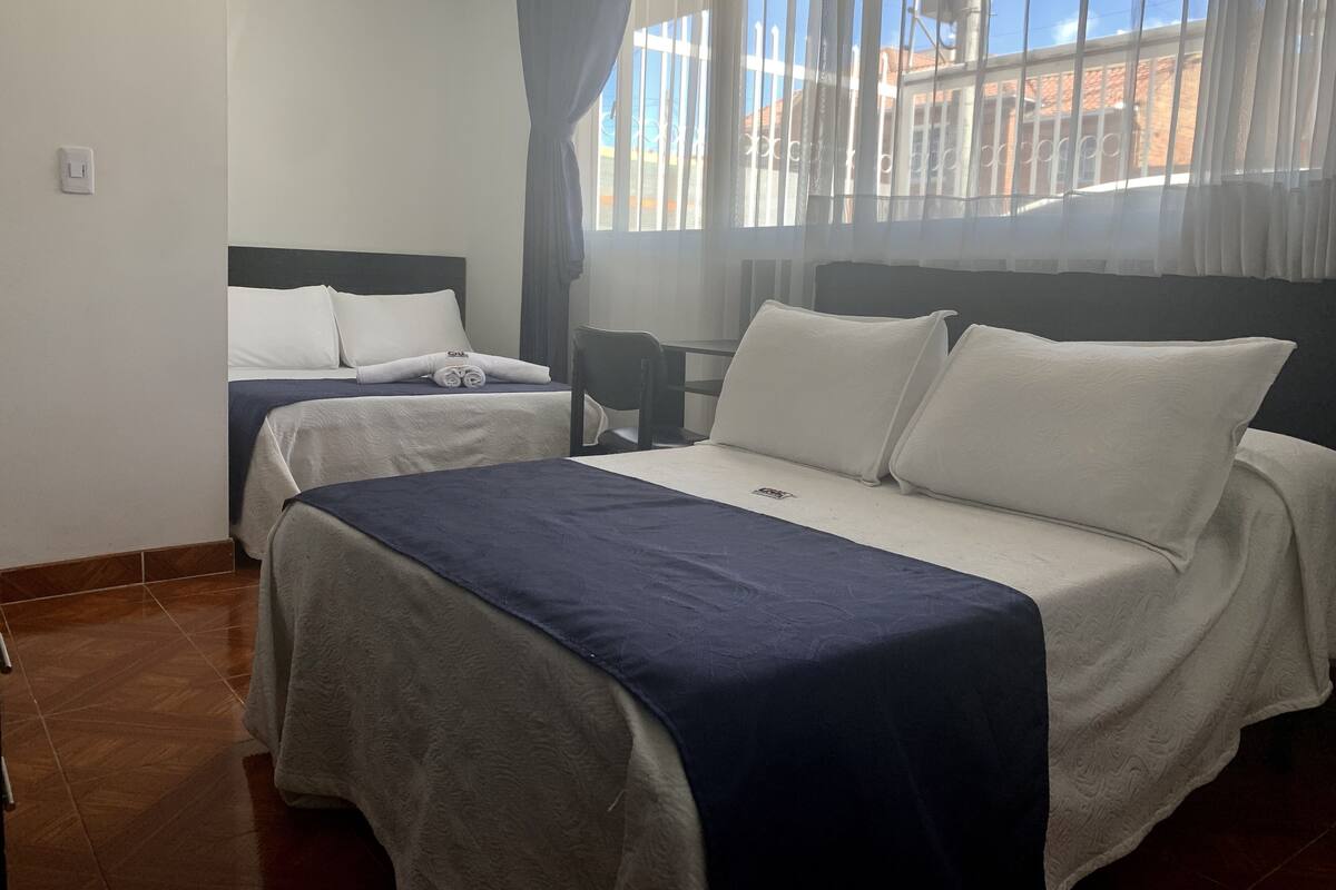 Una habitación de hotel con dos camas, una silla y una ventana con cortinas.