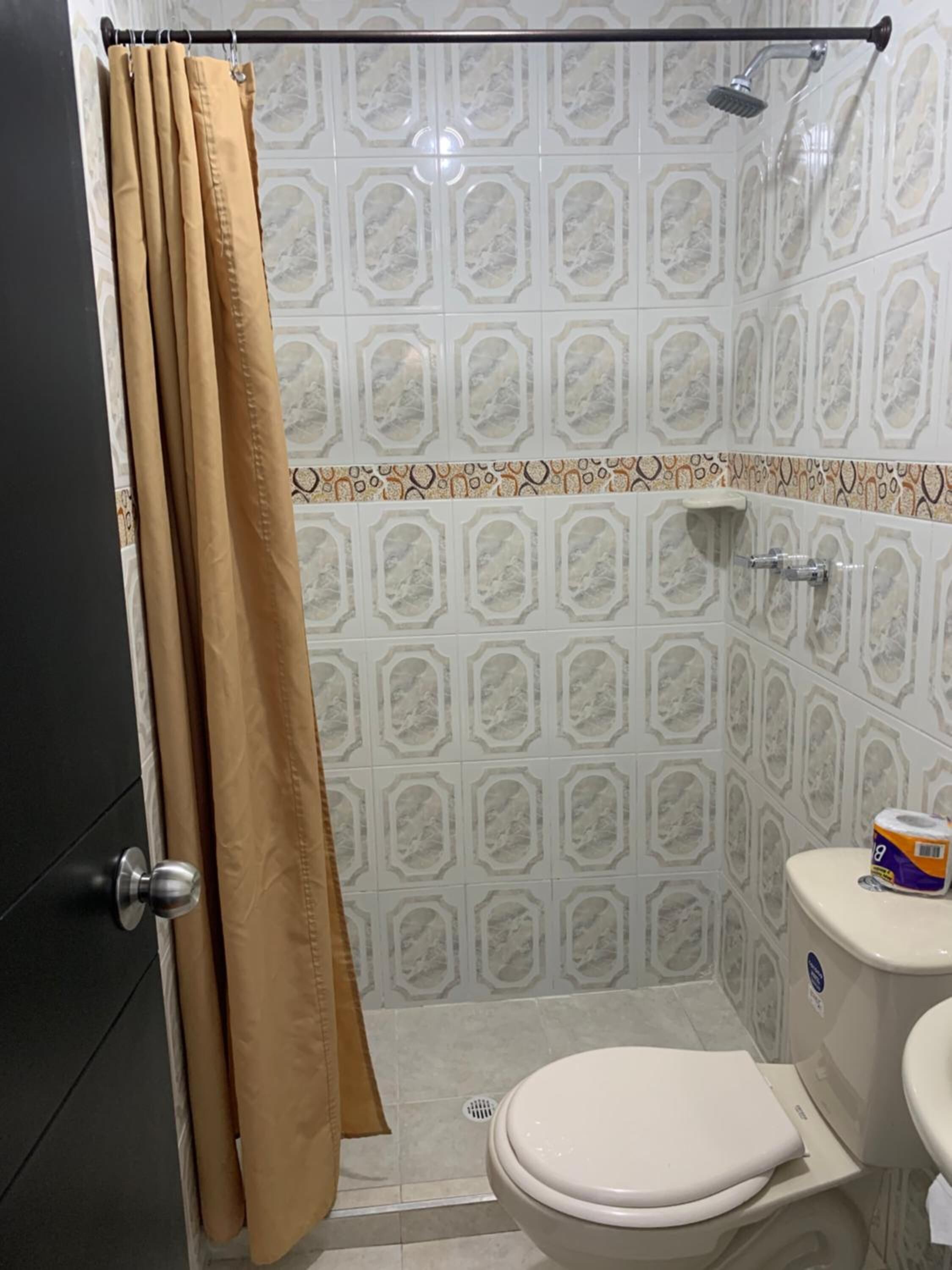 A bathroom with a toilet, sink, shower, and patterned tiles.