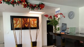 Un área de recepción con una obra de arte enmarcada, un reloj y un cartel de bienvenida.