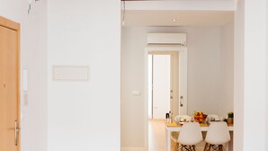 Un salón espacioso con vigas de madera en el techo, una mesa de comedor con sillas y un sofá gris.