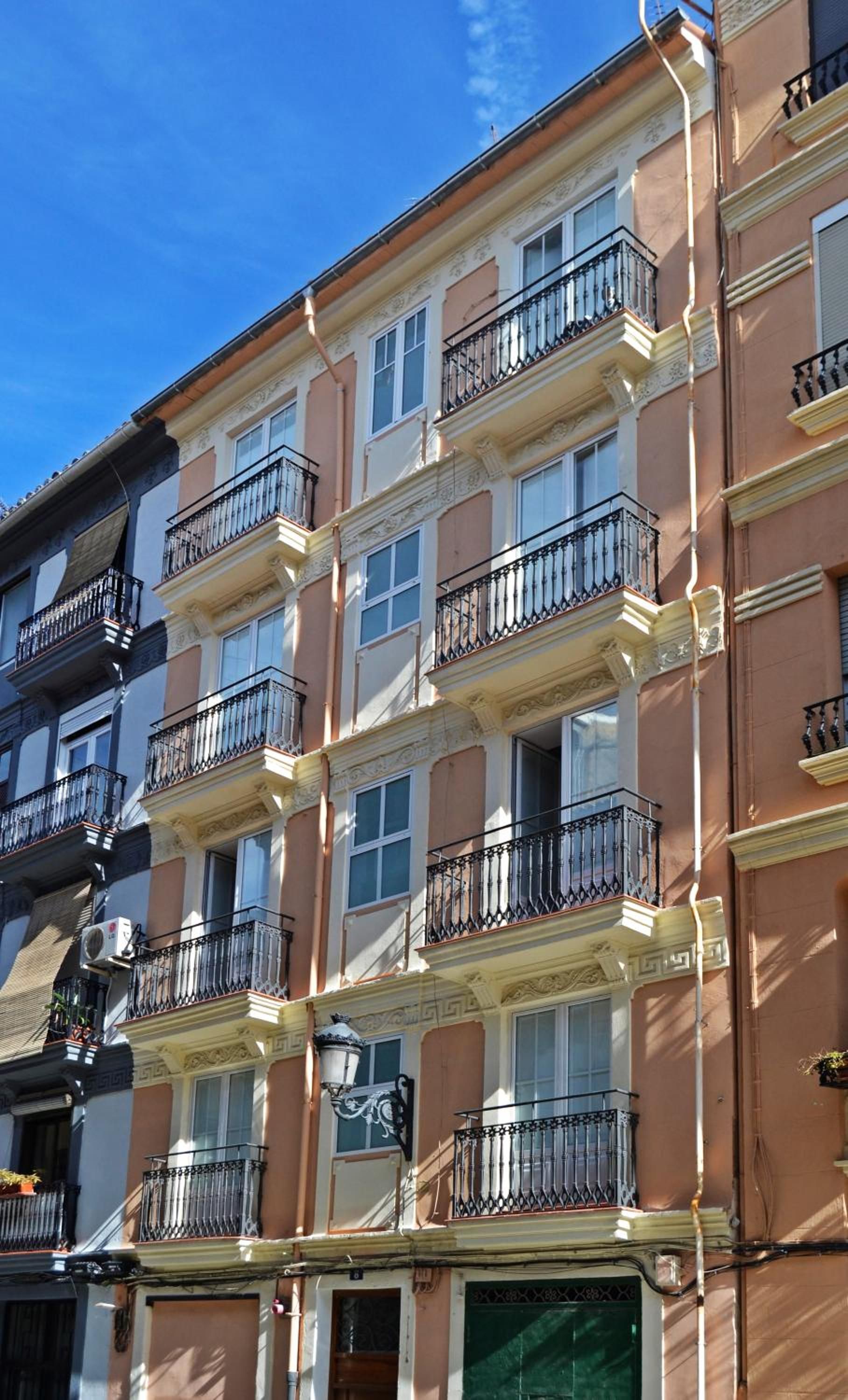 Un immeuble résidentiel à plusieurs étages, doté de balcons, d’une entrée principale et donnant sur la rue.