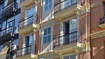 Un immeuble résidentiel à plusieurs étages, doté de balcons, d’une entrée principale et donnant sur la rue.