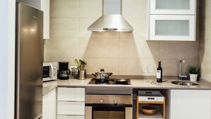 Una cocina moderna con electrodomésticos de acero inoxidable, horno empotrado, extractor de humos y armarios blancos.