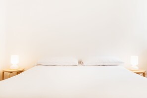 Una cama bien hecha con dos almohadas y dos mesitas de noche con lámparas.
