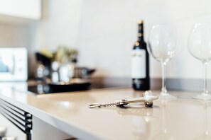 Una encimera de cocina con una botella de vino, dos copas de vino y un sacacorchos.