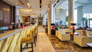 Un moderno vestíbulo de hotel con zona de bar, asientos y grandes ventanales.
