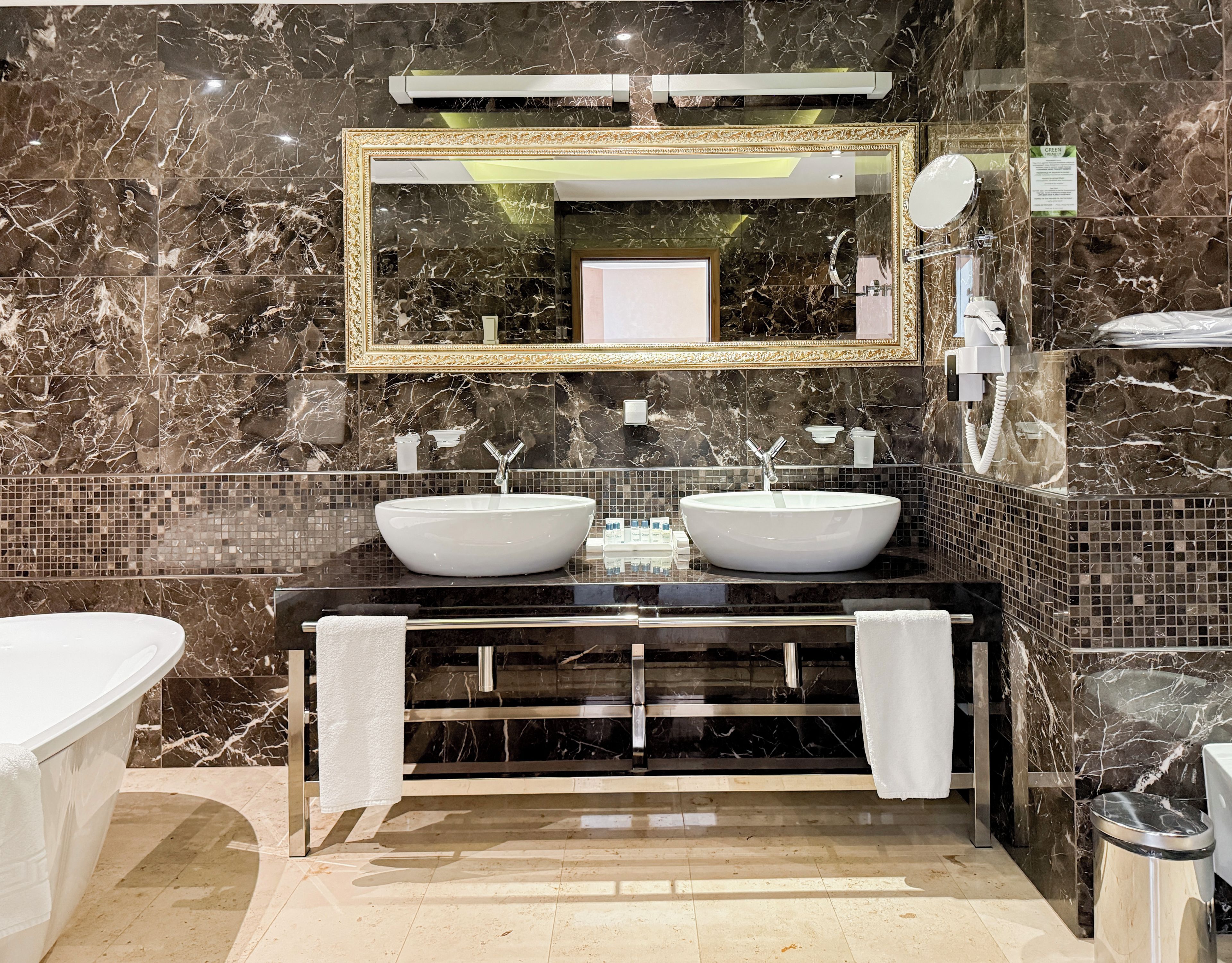 A bathroom with two sinks, a large mirror, and a bathtub.