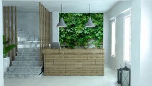 A modern interior with a wooden reception desk, a stone staircase, and a green wall with plants. - Philoxenia Earia (Volvi)