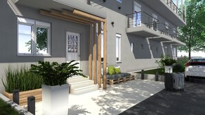 A modern apartment building with a clean design, large windows, and a small outdoor seating area. - Philoxenia Earia (Volvi)