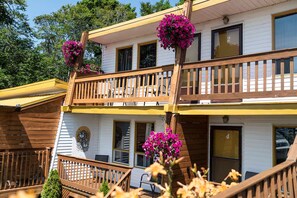 A two-story building with a balcony, wooden railings, and flower baskets. - Motel Île d'Orléans (Saint-Laurent-de-l'ile d'Orleans)