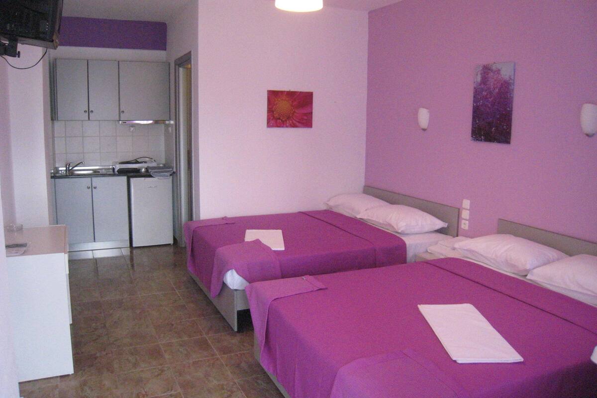 Una habitación de hotel con dos camas, un kitchenette y un baño.