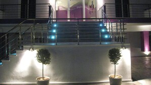 A building with a staircase leading to a landing, a balcony, and two potted plants. - Philoxenia Evgenia (Volvi)