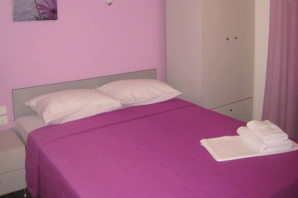 Una habitación con cama, armario y un cuadro en la pared.