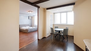 Een kamer met een bed, een eettafel met stoelen en een raam.