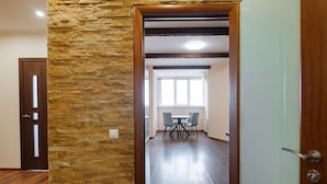 Een kamer met een stenen muur, een houten deur en een eethoek met een tafel en stoelen.