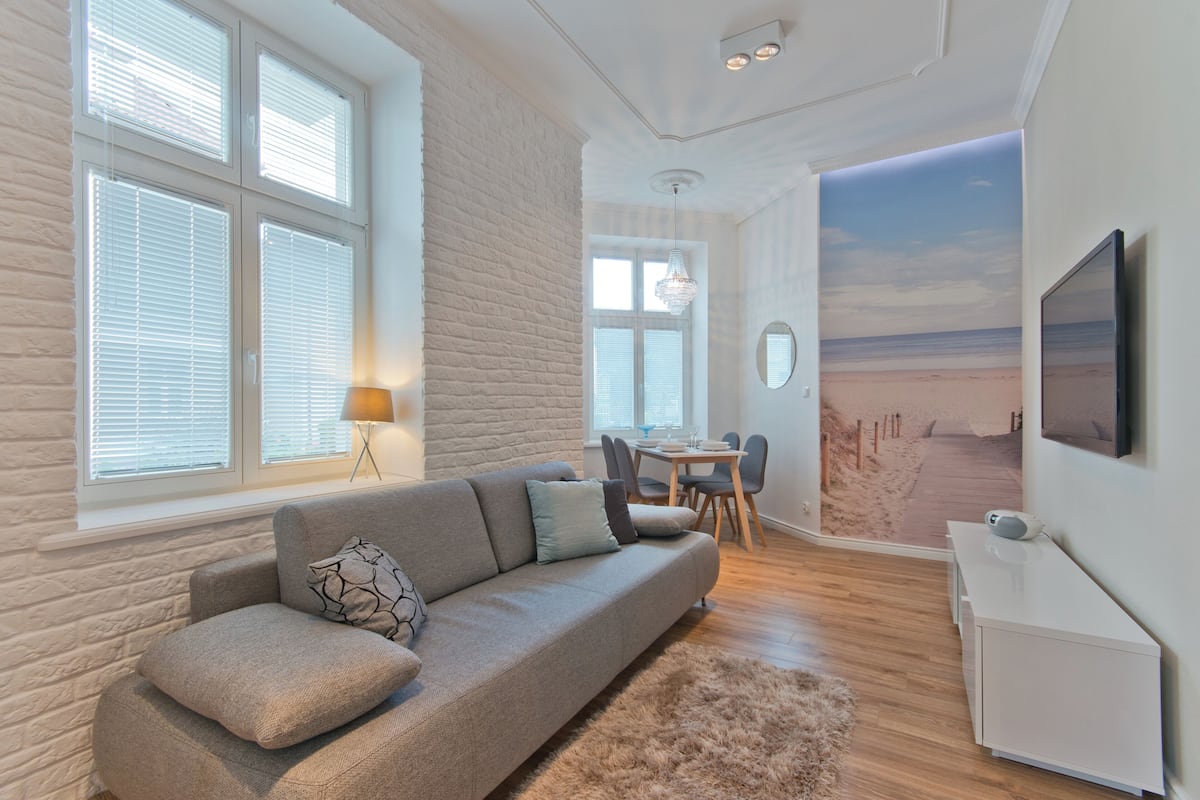 A modern living room with a sofa, a dining table, and a TV.