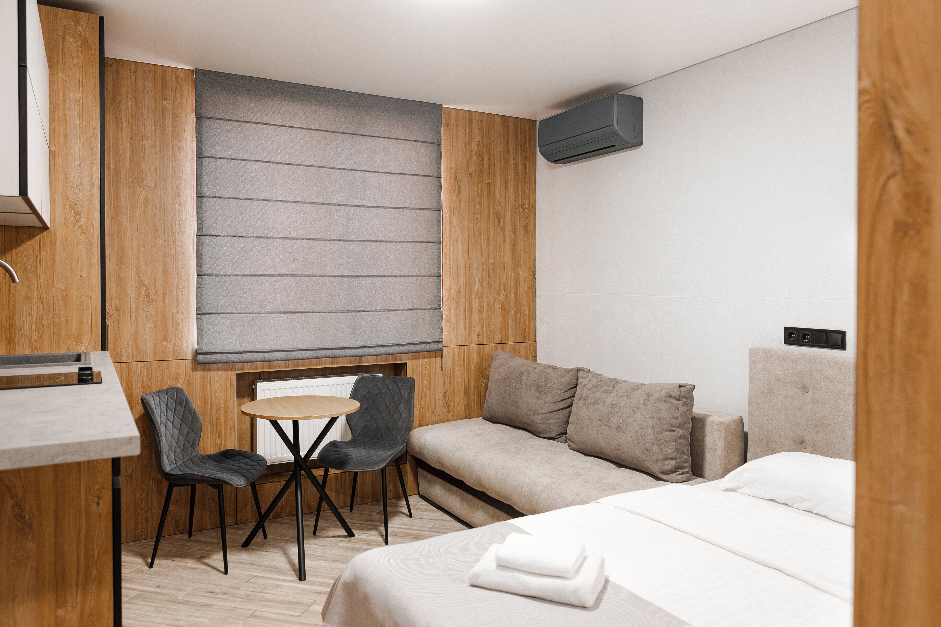 A modern hotel room with a bed, a sofa, a small table, and two chairs.