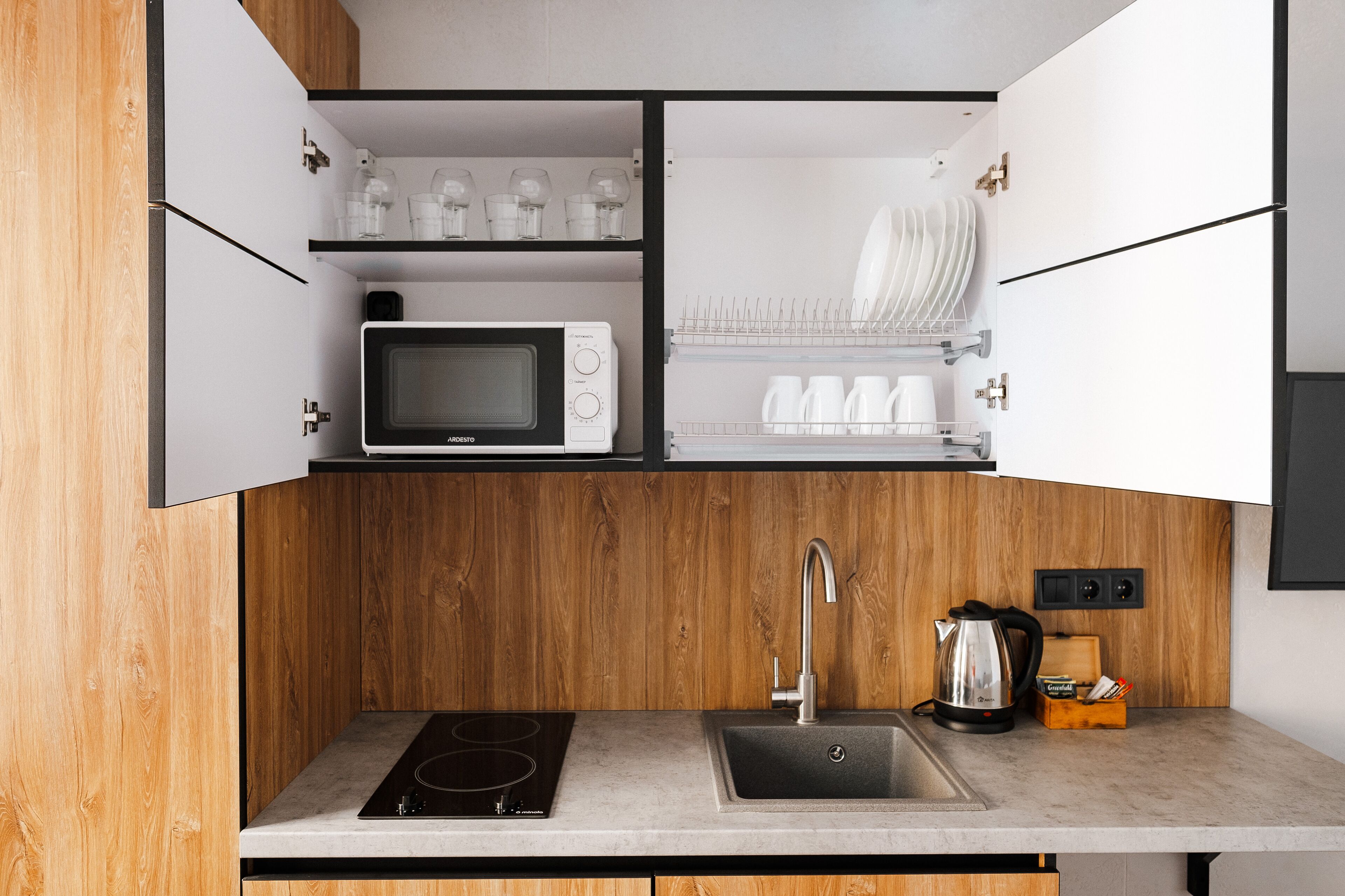 Une cuisine moderne équipée d’un four à micro-ondes encastré, d’un évier et d’un plan de travail en bois.