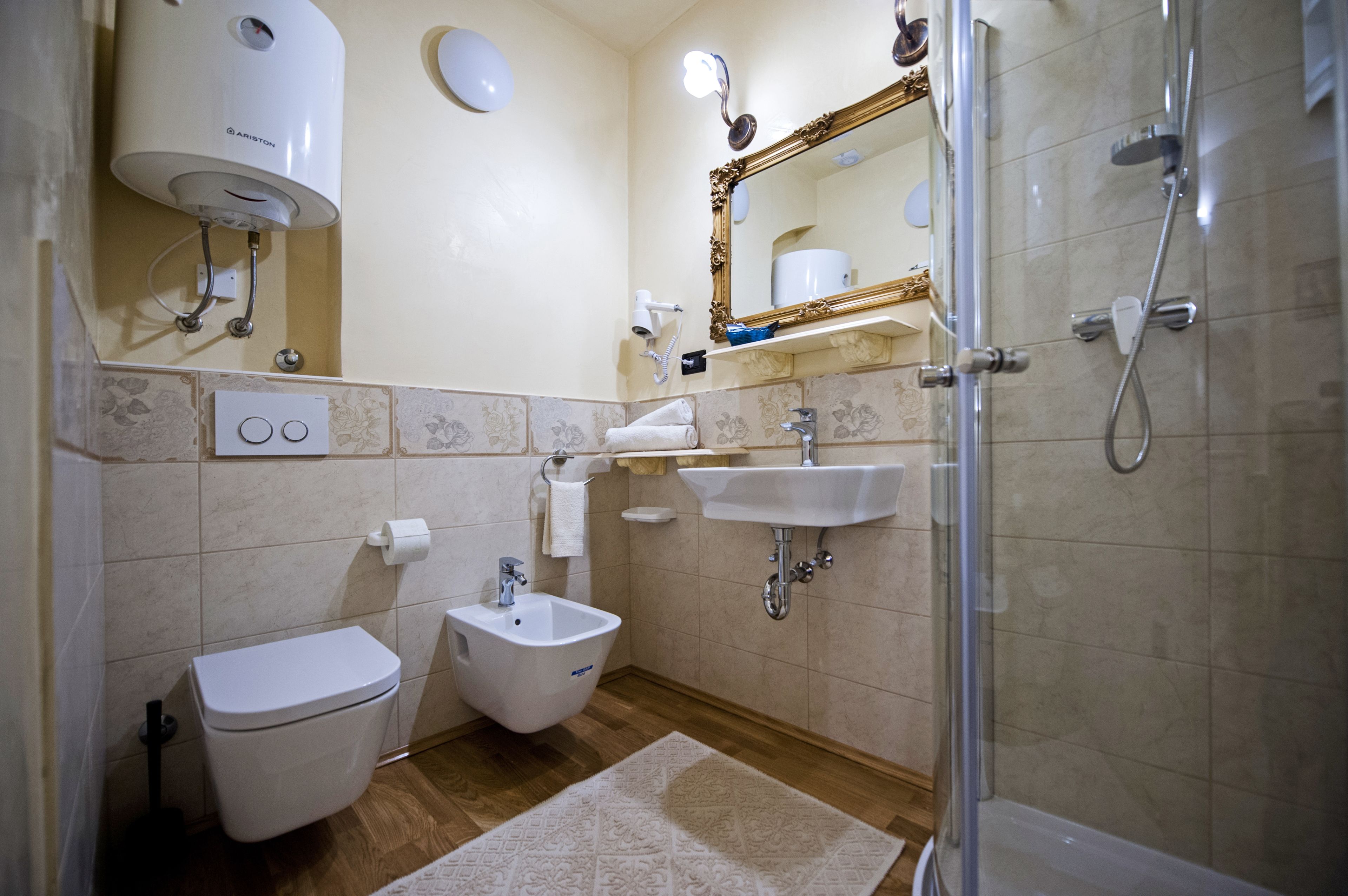 Une salle de bain comprenant des toilettes, un bidet, un lavabo, un miroir et une douche.