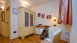 A room with a white armchair, a wooden floor, a cabinet with patterned doors, and wall-mounted artwork. - Studios Antica Porta Sul Mar (Rovinj)