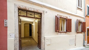 A building entrance with a wooden door, a metal gate, and a hallway leading inside. - Studios Antica Porta Sul Mar (Rovinj)