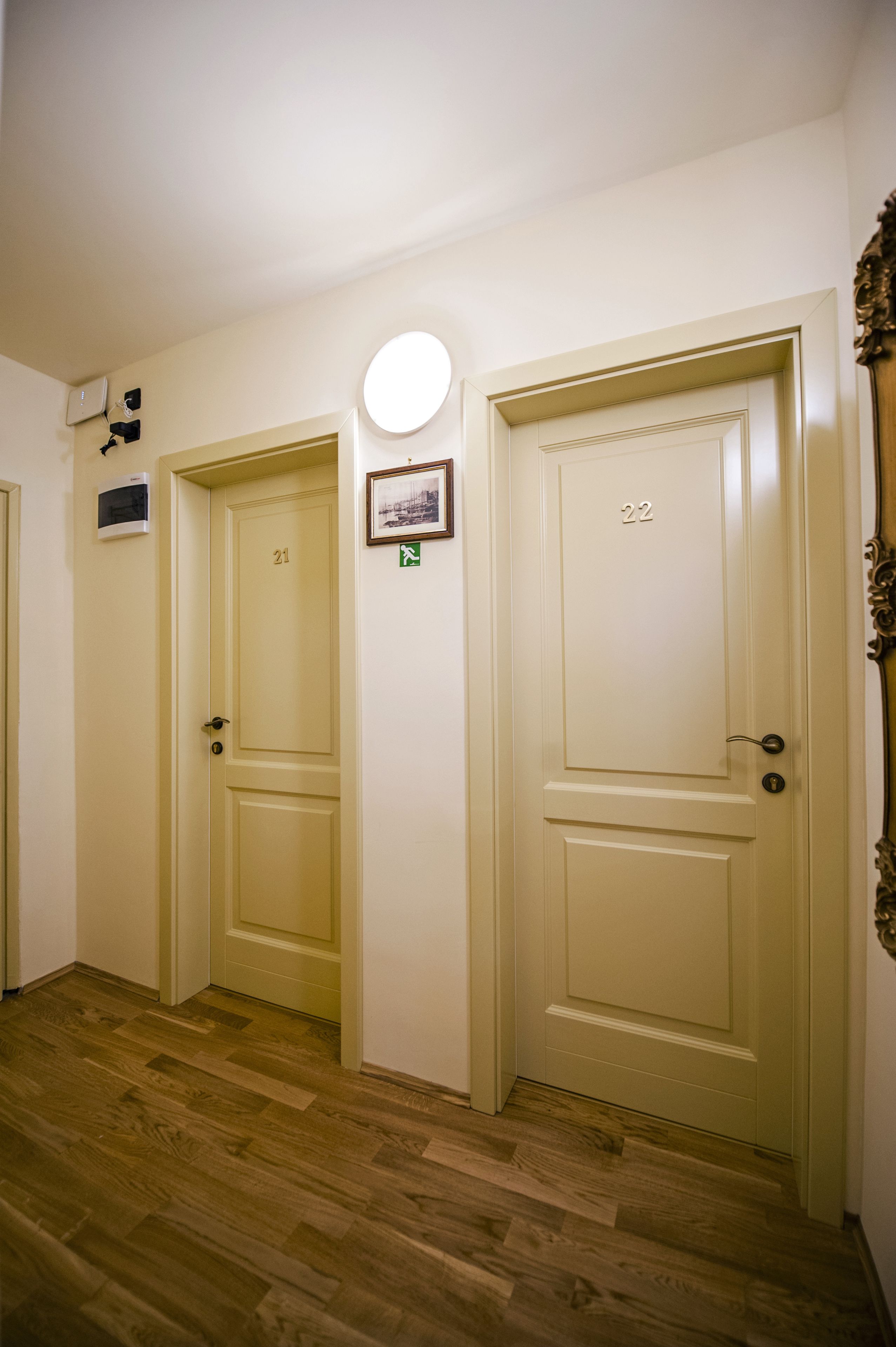 A hallway with three doors, numbered 21, 22, and 23, and a small framed picture on the wall.