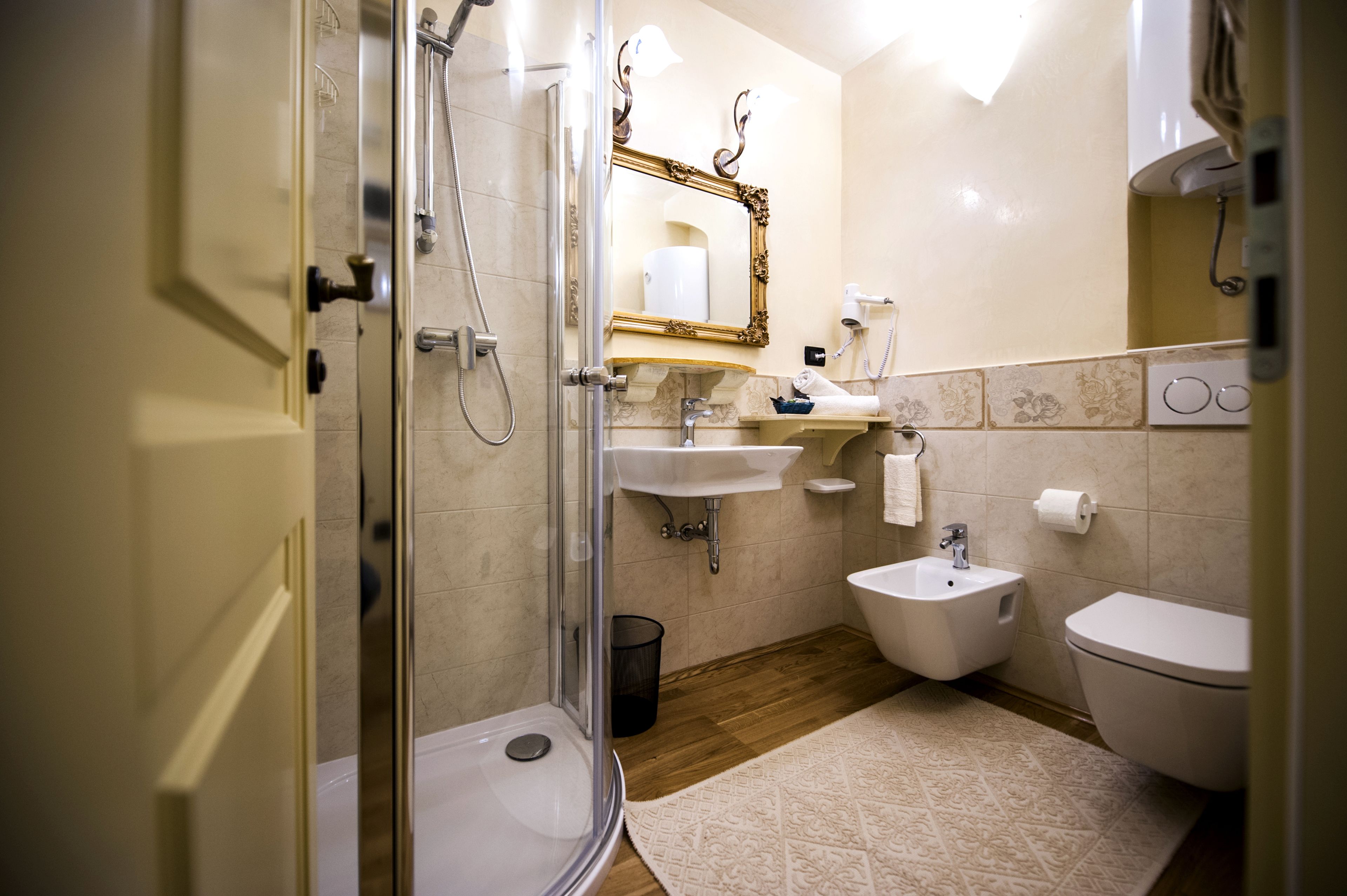 A modern bathroom with a glass-enclosed shower, a white sink, a bidet, and a toilet.