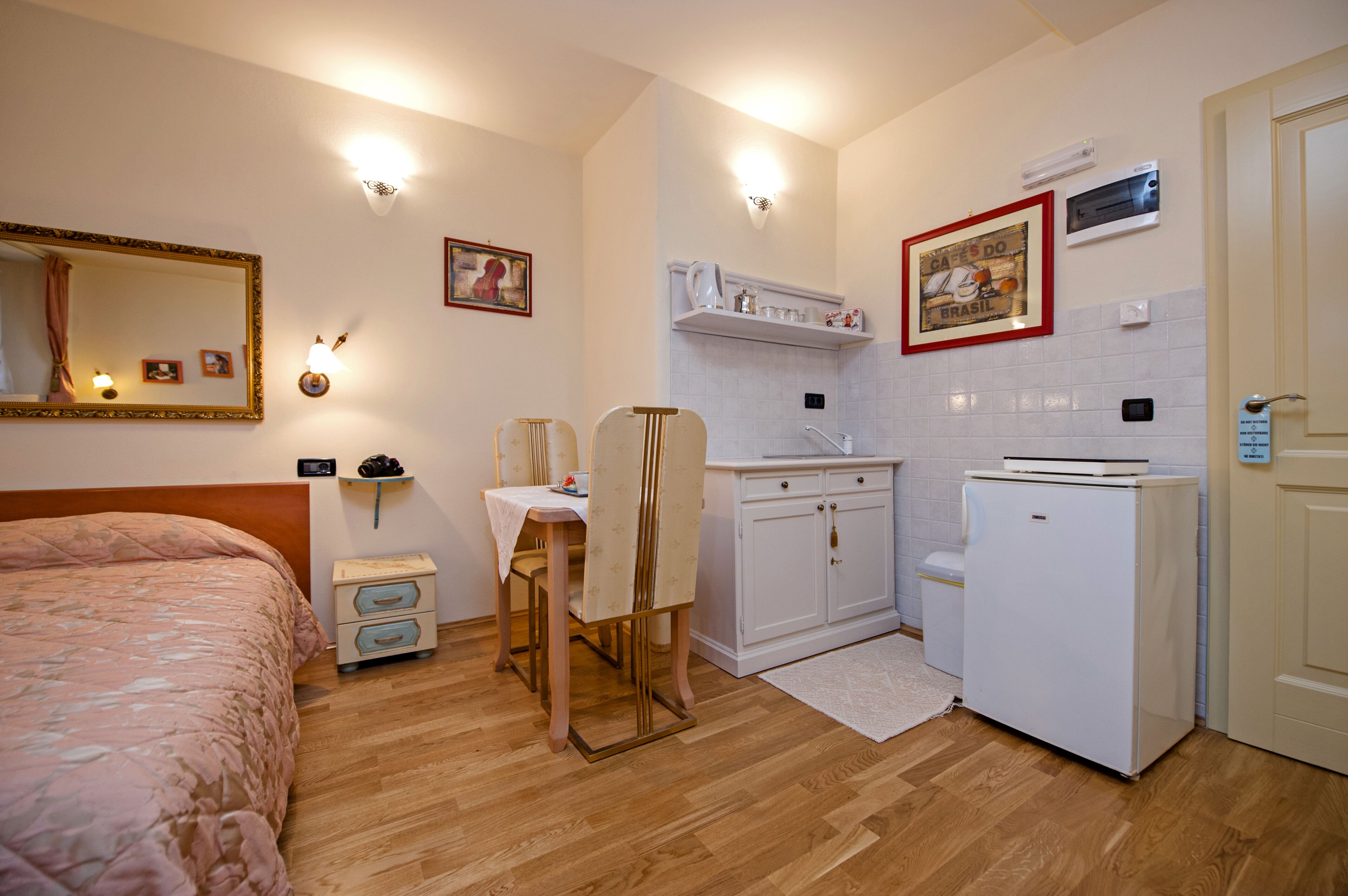 Une chambre d’hôtel de taille réduite, comprenant un lit, une petite table à manger, une chaise, un coin cuisine et une salle de bain.