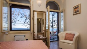A bedroom with a large bed, a chair, and a view of the sea through a window. - Studios Antica Porta Sul Mar (Rovinj)