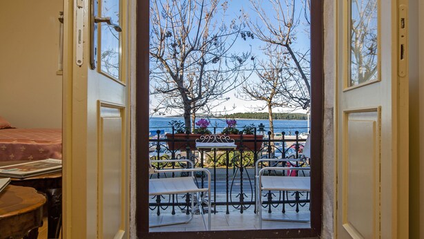An open door leading to a balcony with outdoor seating and a view of a lake. - Studios Antica Porta Sul Mar (Rovinj)