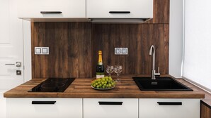 A modern kitchen with a wooden countertop, a built-in stove, a sink, and a wine bottle. - CityApartments Kyiv Palace "Ukraine" (Kyiv)