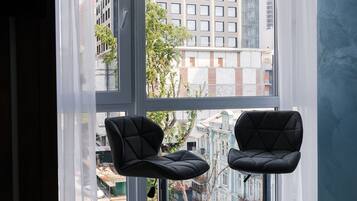 Una habitación moderna con dos taburetes negros y un ventanal con cortinas blancas.