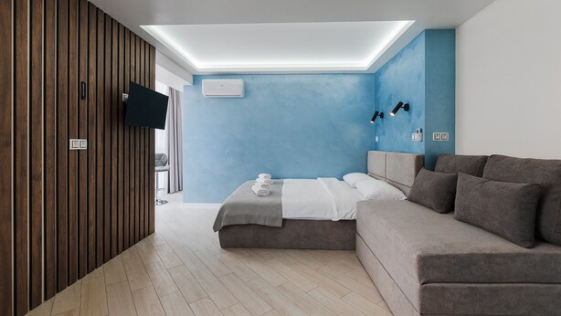 A modern bedroom with a bed, a sofa, a TV, and a skylight. - CityApartments Kyiv Palace "Ukraine" (Kyiv)