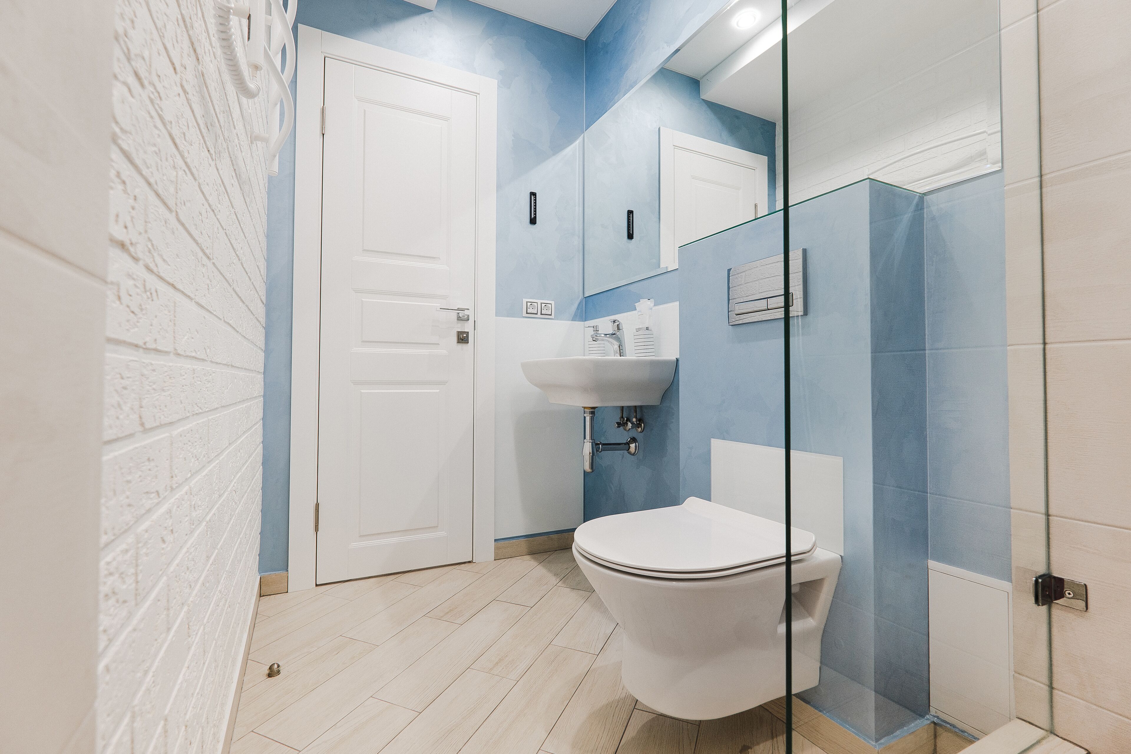 A bathroom with a white toilet, a sink, and a glass shower enclosure.