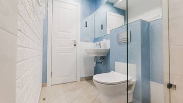 A bathroom with a white toilet, a sink, and a glass shower enclosure.