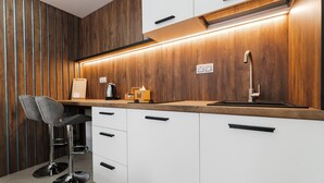 A modern kitchen with wooden paneling, white cabinets, and a stainless steel sink. - CityApartments Kyiv Palace "Ukraine" (Kyiv)