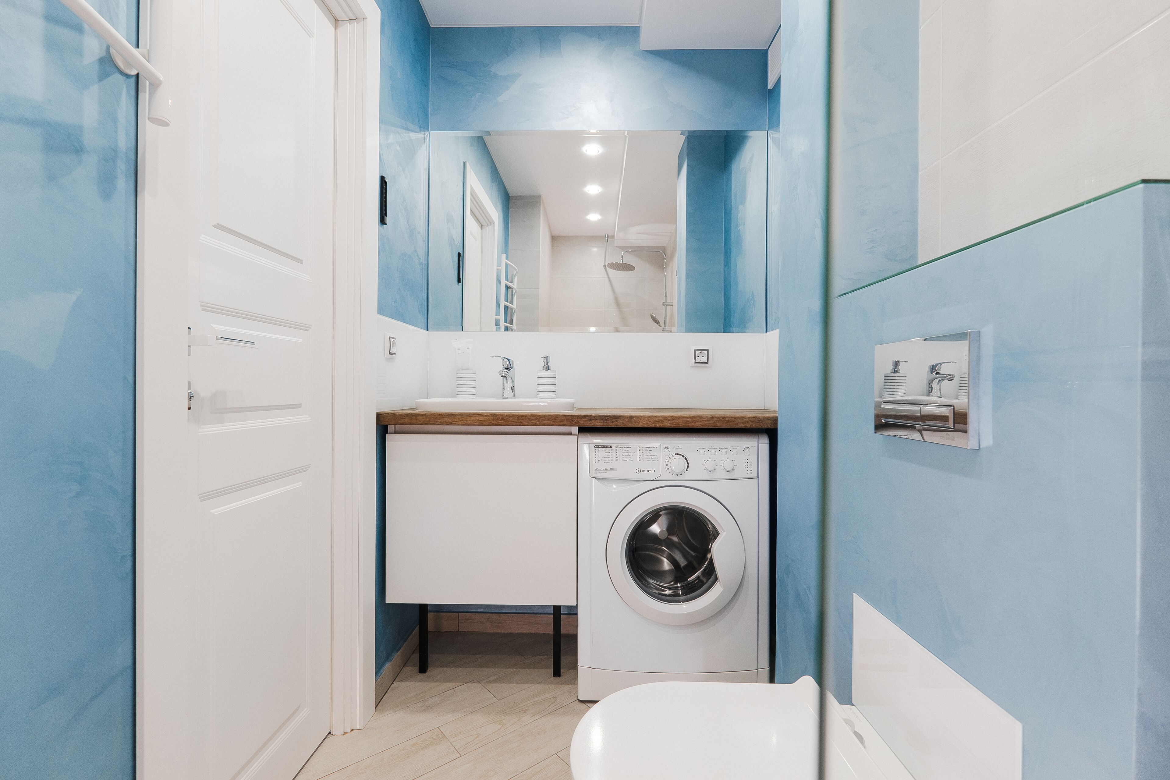 A compact laundry room with a washing machine, a small sink, and a toilet.
