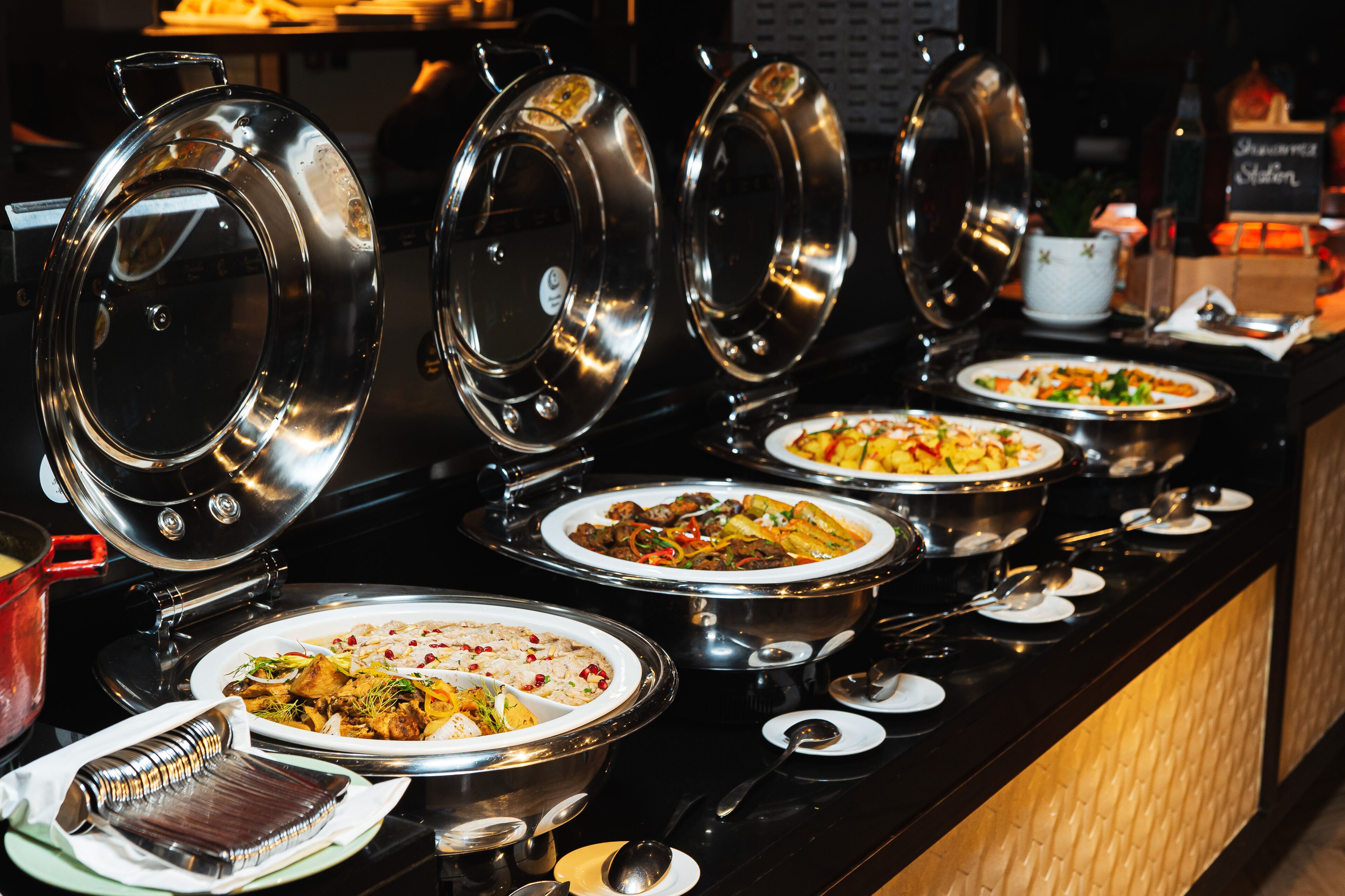 A buffet with multiple food stations, each with a covered serving dish.